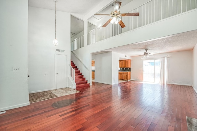 3340 N Dante Ave, Fresno, CA 93722 - unfurnished living room featuring a ceiling fan, hardwood / wood-style floors, a high ceiling, stairway, and beam ceiling