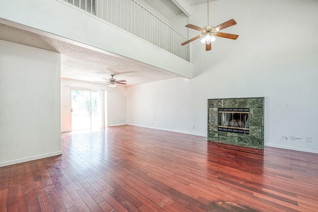 3340 N Dante Ave, Fresno, CA 93722 - unfurnished living room featuring a ceiling fan, high vaulted ceiling, a tiled fireplace, and wood finished floors