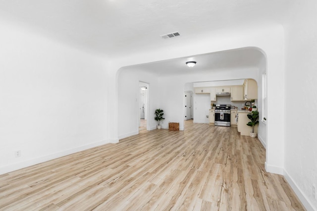1022 N Carruth Ave, Fresno, CA 93728 - unfurnished living room featuring arched walkways and light wood-style flooring