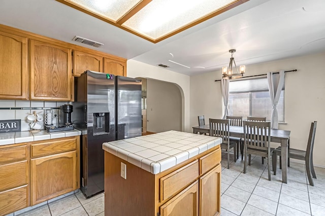 2687 Fowler Ave, Clovis, CA 93611 - kitchen with stainless steel fridge with ice dispenser, arched walkways, tile counters, light tile patterned flooring, and a chandelier