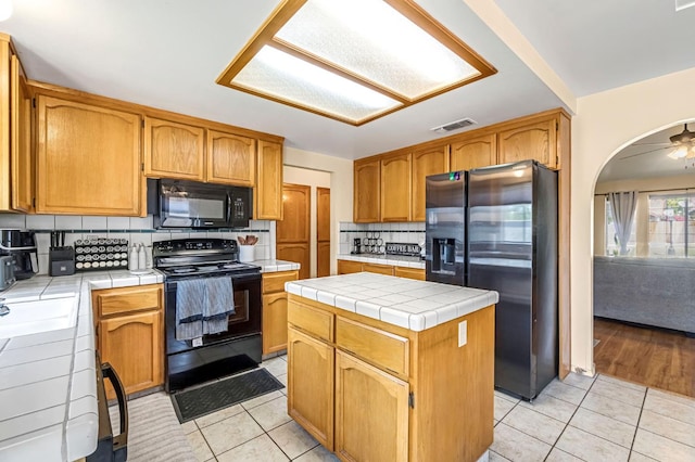 2687 Fowler Ave, Clovis, CA 93611 - kitchen featuring black appliances, tile counters, light tile patterned floors, backsplash, and a center island