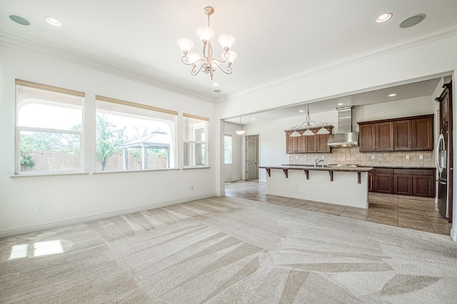 2593 E Utah, Fresno, CA 93720 - kitchen featuring wall chimney range hood, a breakfast bar area, a chandelier, ornamental molding, and open floor plan