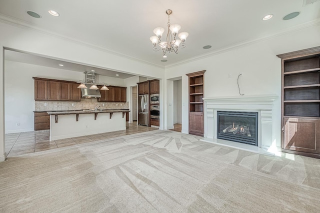 2593 E Utah, Fresno, CA 93720 - unfurnished living room featuring a chandelier, built in shelves, light colored carpet, a glass covered fireplace, and crown molding