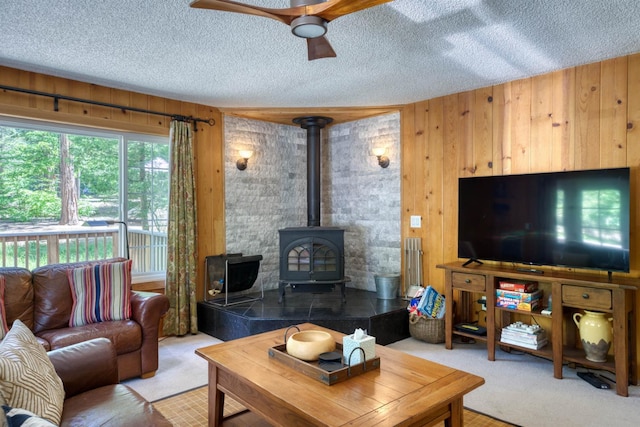 42055 Saddleback Rd, Shaver Lake, CA 93664 - living room with a wood stove, carpet floors, wooden walls, ceiling fan, and a textured ceiling