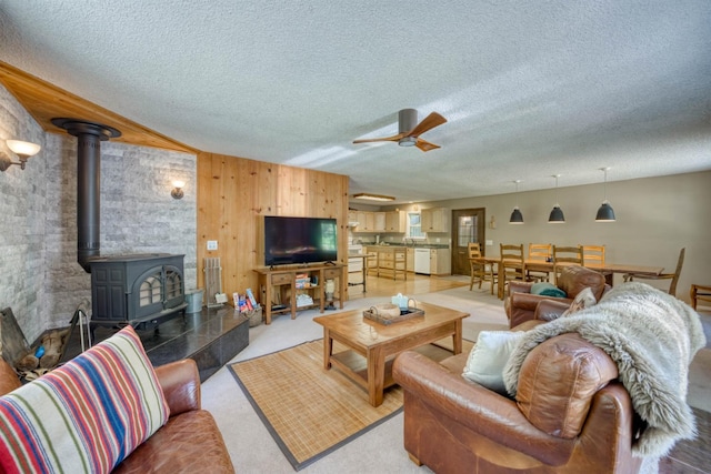 42055 Saddleback Rd, Shaver Lake, CA 93664 - living room featuring a wood stove, a ceiling fan, a textured ceiling, and wooden walls