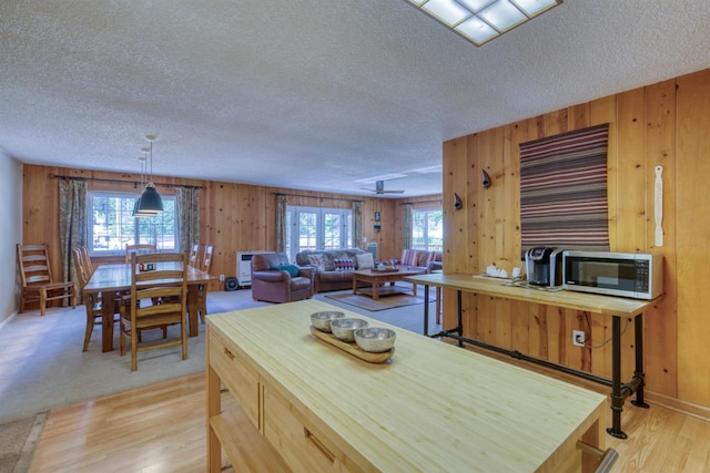 42055 Saddleback Rd, Shaver Lake, CA 93664 - kitchen with stainless steel microwave, a textured ceiling, light wood-style flooring, and wooden walls