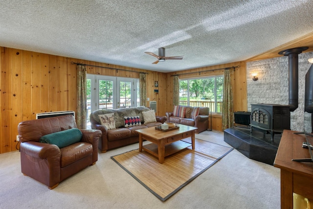 42055 Saddleback Rd, Shaver Lake, CA 93664 - living room with a textured ceiling, ceiling fan, a wood stove, wooden walls, and carpet floors