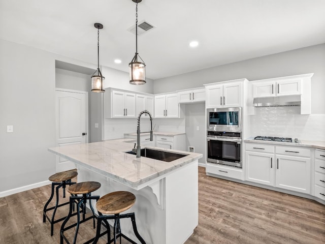 180 N Anderson Ave, Clovis, CA 93612 - kitchen featuring appliances with stainless steel finishes, light wood-style floors, light stone counters, white cabinets, and under cabinet range hood