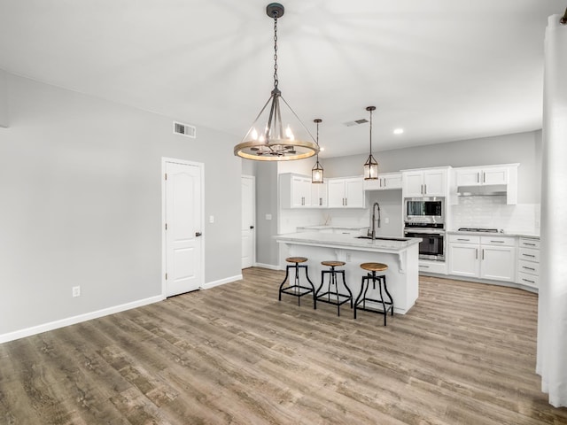 180 N Anderson Ave, Clovis, CA 93612 - kitchen with stainless steel appliances, light wood-type flooring, backsplash, white cabinets, and light countertops