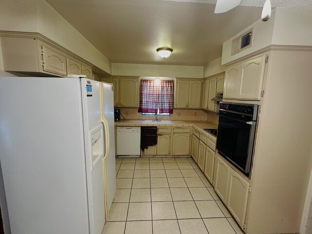 3043 N Brunswick Ave, Fresno, CA 93722 - kitchen with black appliances, light tile patterned floors, tile countertops, under cabinet range hood, and backsplash