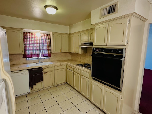 3043 N Brunswick Ave, Fresno, CA 93722 - kitchen featuring black oven, dishwasher, tile counters, under cabinet range hood, and light tile patterned floors