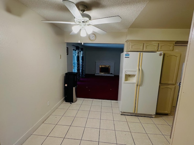 3043 N Brunswick Ave, Fresno, CA 93722 - kitchen featuring white refrigerator with ice dispenser, a textured ceiling, a brick fireplace, ceiling fan, and light tile patterned flooring