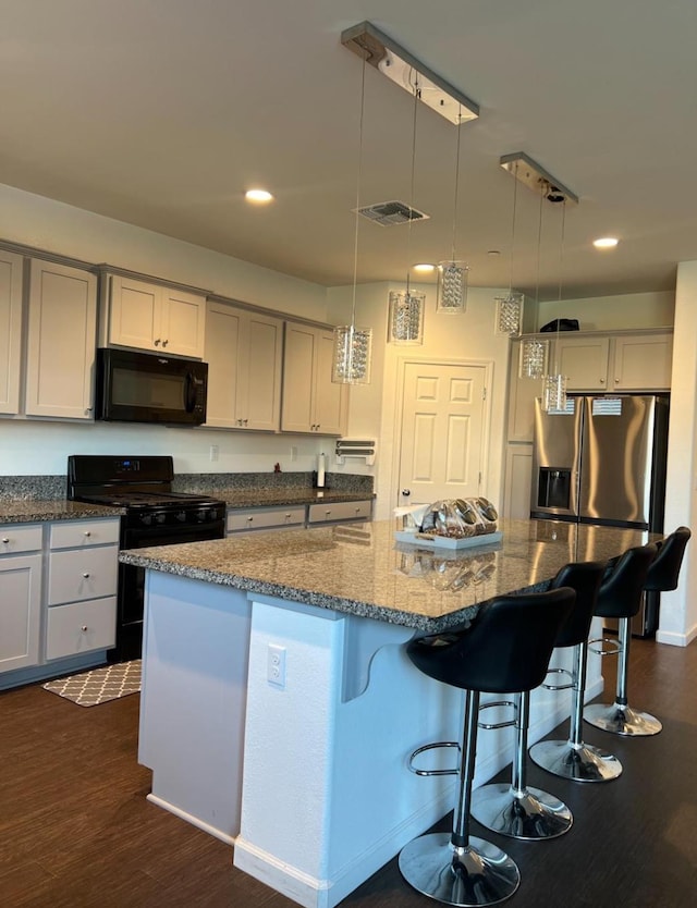4542 N Casey Ave, Fresno, CA 93723 - kitchen with black appliances, dark stone counters, recessed lighting, a breakfast bar area, and hanging light fixtures