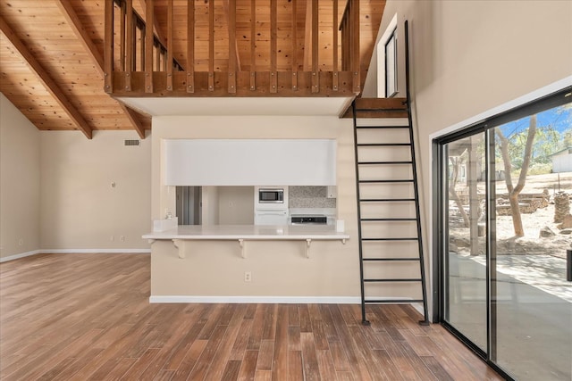 42617 John Muir Dr, Coarsegold, CA 93614 - kitchen featuring a wood ceiling with exposed beams, wood finished floors, a breakfast bar, stainless steel microwave, and high vaulted ceiling