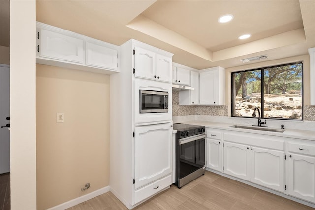 42617 John Muir Dr, Coarsegold, CA 93614 - kitchen featuring appliances with stainless steel finishes, a tray ceiling, white cabinets, backsplash, and light countertops