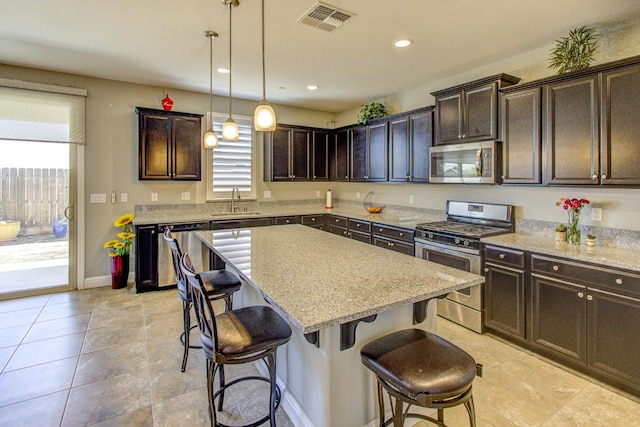 2286 N Janice Ave, Fresno, CA 93737 - kitchen featuring appliances with stainless steel finishes, plenty of natural light, a breakfast bar, dark brown cabinetry, and recessed lighting