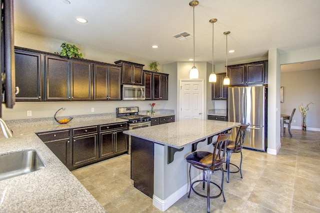 2286 N Janice Ave, Fresno, CA 93737 - kitchen with appliances with stainless steel finishes, dark brown cabinets, a center island, light stone counters, and recessed lighting