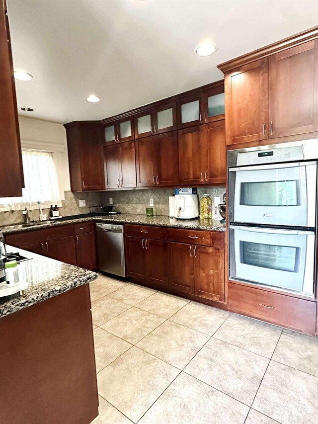 3728 E Huntington Blvd, Fresno, CA 93702 - kitchen with appliances with stainless steel finishes, backsplash, dark stone countertops, glass insert cabinets, and recessed lighting