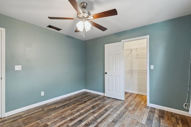 2111 Birch Ave, Clovis, CA 93611 - unfurnished bedroom with a closet, dark wood-style flooring, a spacious closet, and ceiling fan