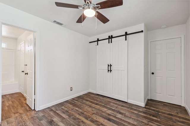 2111 Birch Ave, Clovis, CA 93611 - unfurnished bedroom featuring a barn door, dark wood finished floors, a closet, and ensuite bath