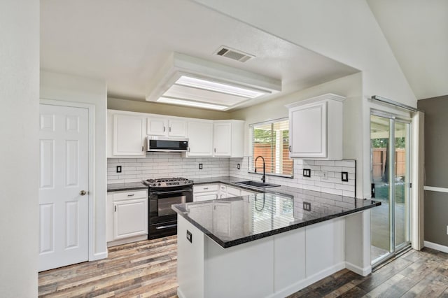 2111 Birch Ave, Clovis, CA 93611 - kitchen featuring black range with gas stovetop, stainless steel microwave, wood finished floors, white cabinets, and a peninsula