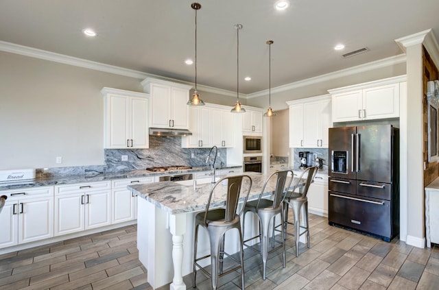 3211 Salem Ave, Clovis, CA 93619 - kitchen with appliances with stainless steel finishes, wood finish floors, under cabinet range hood, white cabinetry, and a kitchen island with sink