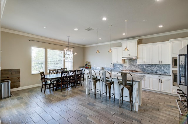 3211 Salem Ave, Clovis, CA 93619 - kitchen with tasteful backsplash, light stone countertops, white cabinets, a breakfast bar area, and a center island with sink