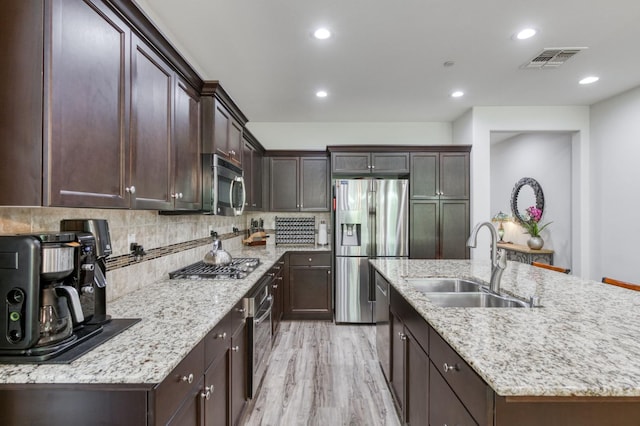 3562 Luminary Way, Clovis, CA 93619 - kitchen featuring appliances with stainless steel finishes, a center island with sink, backsplash, dark brown cabinets, and recessed lighting