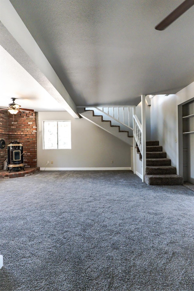 42560 Ranger Circle Way, Coarsegold, CA 93614 - unfurnished living room with a wood stove, stairs, a ceiling fan, carpet flooring, and a textured ceiling