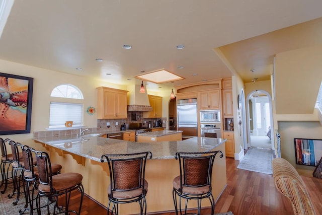 325 Juanita Ave, Oceano, CA 93445 - kitchen featuring built in appliances, wall chimney range hood, light brown cabinetry, tasteful backsplash, and dark wood-style floors