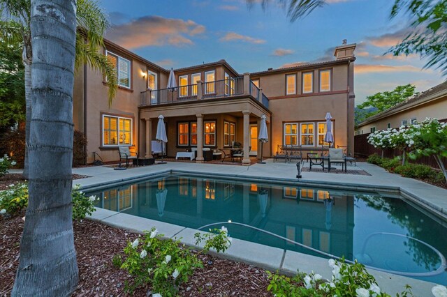 10615 E Landmark Way, Clovis, CA 93619 - back of house at dusk with a balcony, a patio, stucco siding, an outdoor pool, and outdoor lounge area