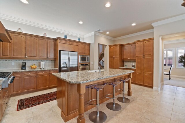 10615 E Landmark Way, Clovis, CA 93619 - kitchen with appliances with stainless steel finishes, backsplash, a center island with sink, light stone counters, and brown cabinetry