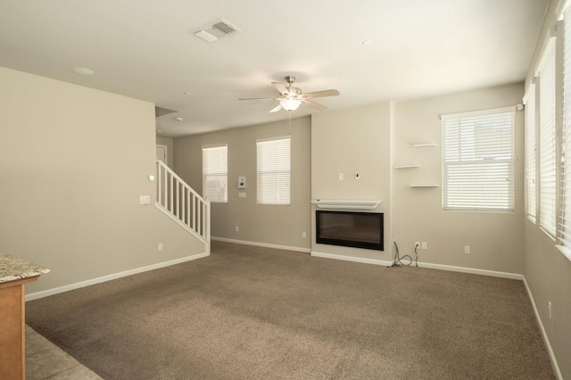 3482 Elevations Way, Clovis, CA 93619 - unfurnished living room featuring a ceiling fan, carpet flooring, a glass covered fireplace, and stairway