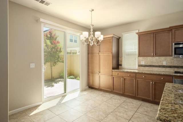 3482 Elevations Way, Clovis, CA 93619 - kitchen featuring stainless steel microwave, a chandelier, tasteful backsplash, pendant lighting, and light tile patterned floors