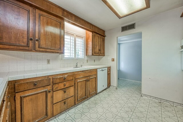 5578 E Perrin Rd, Clovis, CA 93619 - kitchen featuring white dishwasher, light flooring, brown cabinets, and decorative backsplash