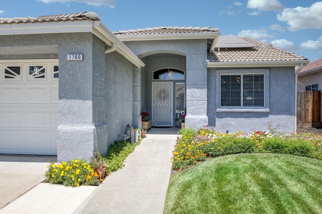 1760 E Ticonderoga Dr, Fresno, CA 93720 - property entrance with an attached garage, stucco siding, roof mounted solar panels, and a tiled roof