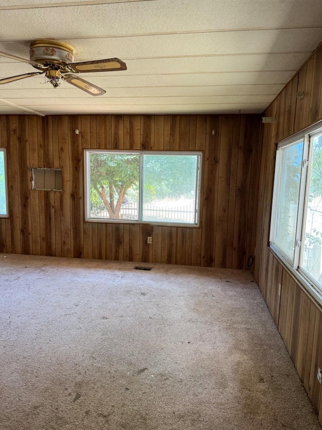 50481 Sundew Rd, Yokuts Valley, CA 93675 - spare room with healthy amount of natural light, carpet floors, wooden walls, and a ceiling fan