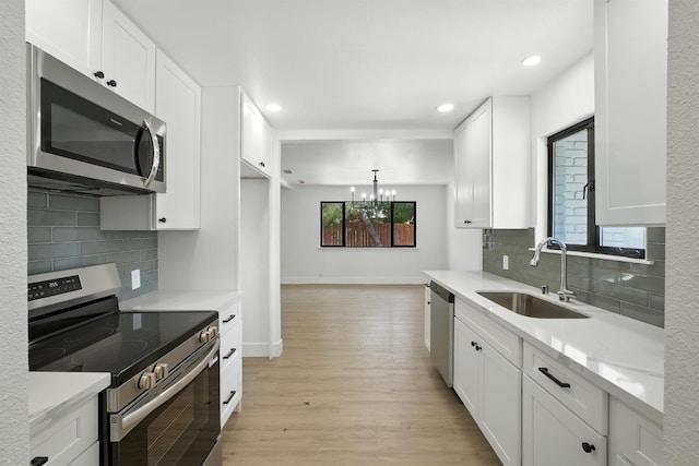 4506 N Angus St, Fresno, CA 93726 - kitchen featuring appliances with stainless steel finishes, light wood-style floors, a chandelier, white cabinetry, and tasteful backsplash