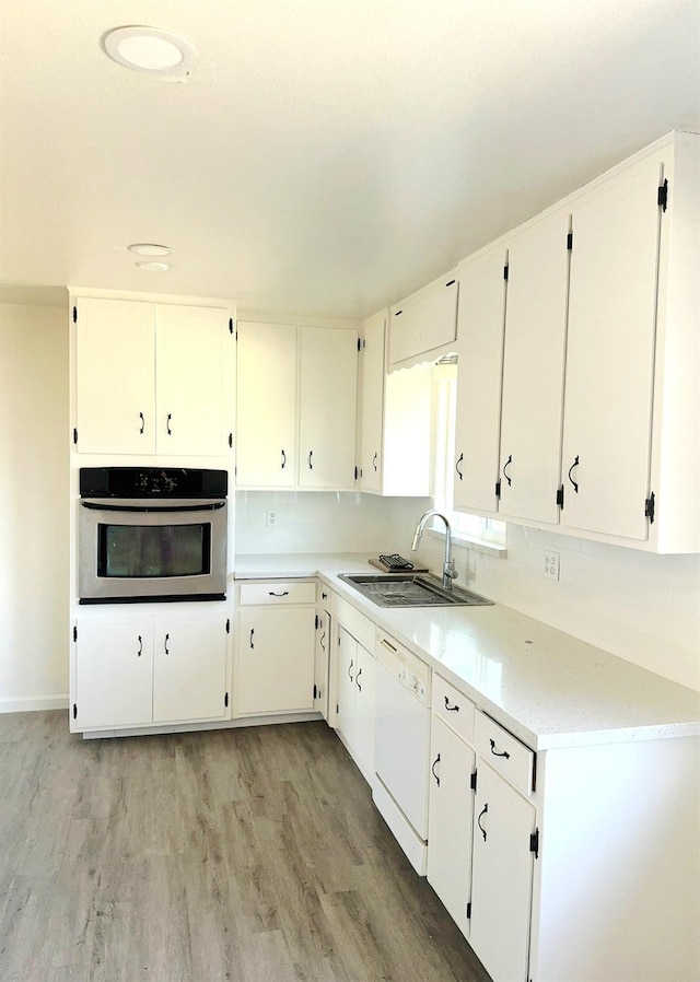 3122 Belmira Rd, Atwater, CA 95301 - kitchen featuring stainless steel oven, white dishwasher, light wood finished floors, light countertops, and white cabinets