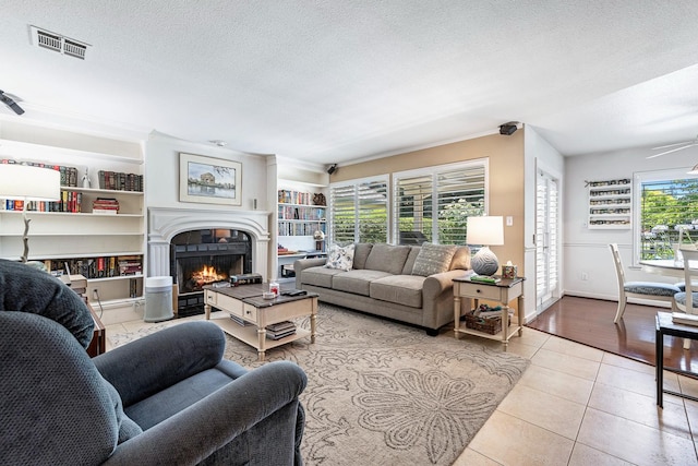3075 W Silverhill Ln, Fresno, CA 93711 - tiled living area with a warm lit fireplace, a textured ceiling, built in features, and ceiling fan