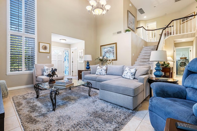 3075 W Silverhill Ln, Fresno, CA 93711 - tiled living area with washer / clothes dryer, stairs, a high ceiling, and a chandelier