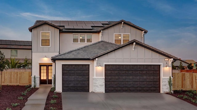 951 Talus Way S, Madera, CA 93636 - view of front facade with board and batten siding, a garage, solar panels, concrete driveway, and french doors