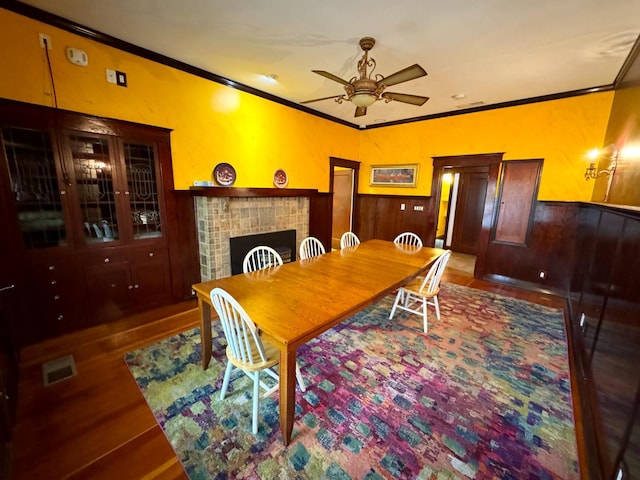 807 N Van Ness Ave, Fresno, CA 93728 - dining area with a ceiling fan, ornamental molding, wood finished floors, a wainscoted wall, and a fireplace