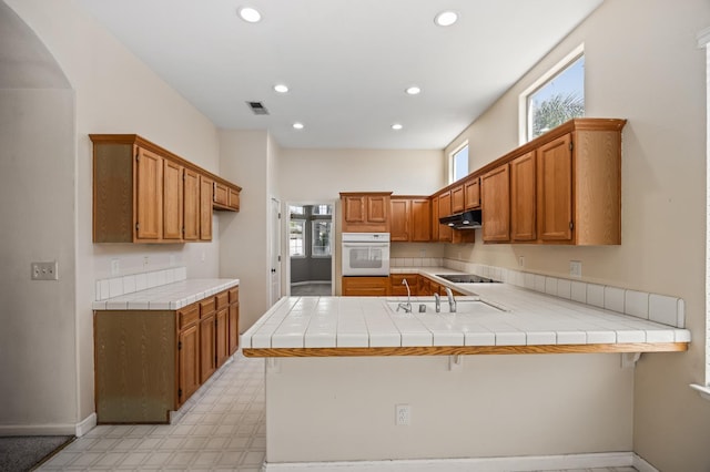 7507 N Constance Ave, Fresno, CA 93722 - kitchen featuring white oven, under cabinet range hood, a peninsula, recessed lighting, and black electric cooktop