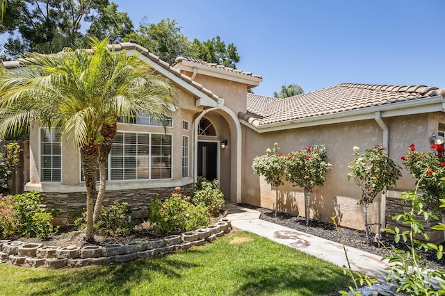 7507 N Constance Ave, Fresno, CA 93722 - view of front of property with a tiled roof, stucco siding, a front yard, and stone siding