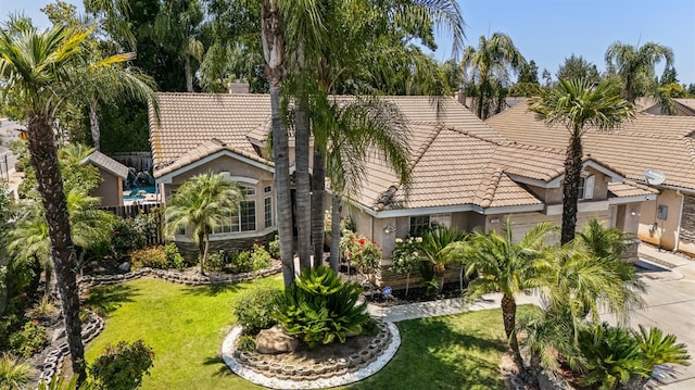 7507 N Constance Ave, Fresno, CA 93722 - exterior space featuring a tile roof, stucco siding, an attached garage, and driveway