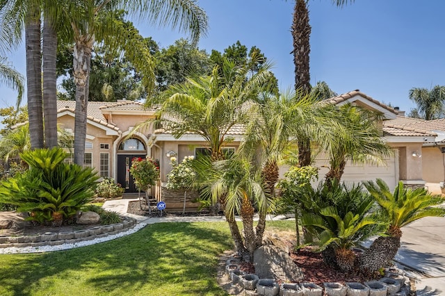 7507 N Constance Ave, Fresno, CA 93722 - mediterranean / spanish-style home with a tile roof, stucco siding, an attached garage, and a front lawn