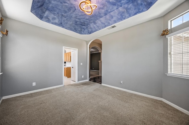 7507 N Constance Ave, Fresno, CA 93722 - spare room with arched walkways, light colored carpet, and a tray ceiling