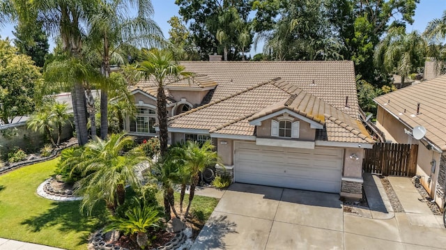7507 N Constance Ave, Fresno, CA 93722 - mediterranean / spanish-style home with a tiled roof, stucco siding, concrete driveway, and a garage