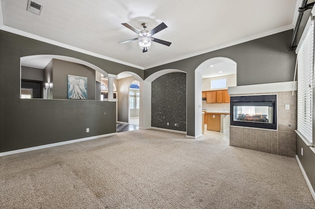 7507 N Constance Ave, Fresno, CA 93722 - unfurnished living room with ceiling fan, light colored carpet, ornamental molding, plenty of natural light, and a tile fireplace